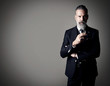 © SFIO CRACHO - Portrait of smoking businessman wearing trendy suit and stands against the empty wall. Horizontal