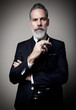 © SFIO CRACHO - Portrait of adult businessman wearing trendy suit and holding cigarette against the empty wall. Vertical
