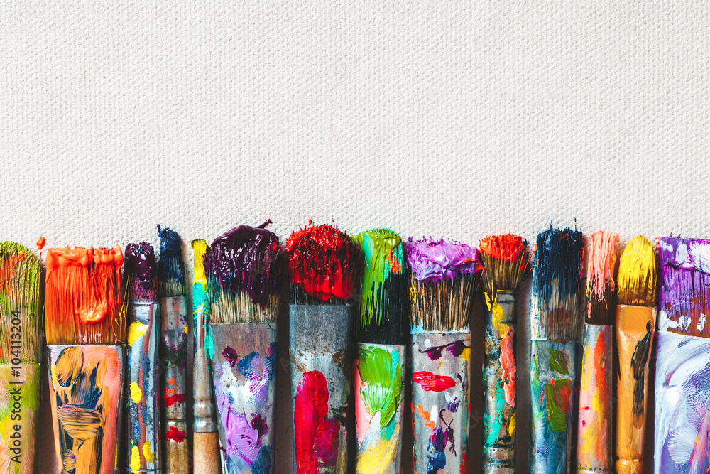 Row of artist paintbrushes closeup on artistic canvas. - obrazy, fototapety, plakaty 