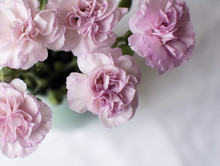 High Angle View Of Pink Carnations In A Green Vase On A White Tablecloth (cropped)