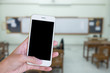 Hands woman are holding touch screen smart phone,tablet on blurred classroom nobody student and teacher  background.