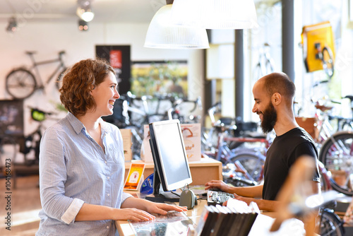 Fotografía Lifestyle Shopping - junge Frau kauft in einem Fahrradladen ein, Beratung durch