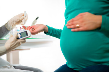 Close-up of a pregnant woman having her blood sugar/ glucose checked.