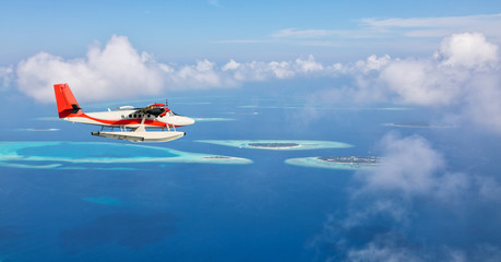 Wall Mural - Sea plane flying above Maldives islands