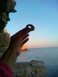 Fototapeta Kamienie - Камень с дырочкой в руке на фоне моря на закате
