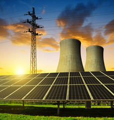 Solar energy panels, nuclear power plant and electricity pylon at sunset.