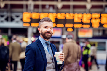 Hipster businessman with coffee cup at the train station