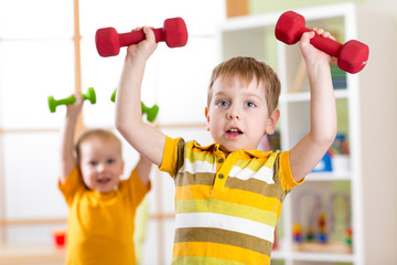 little children boys exercising with dumbbells at home. healthy life, sportive kids.