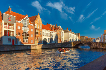 Tourist boat on Bruges canal Spiegelrei in the winter morning, beautiful medieval houses, bridge and reflections, Belgium