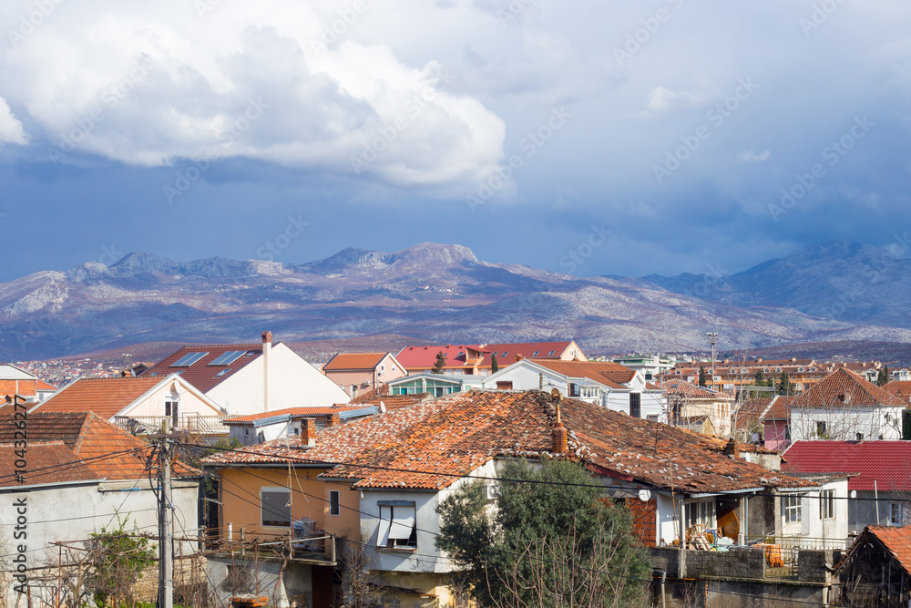 Obraz na płótnie Roofs of Podgorica, Montenegro, mountains and evening sky with clouds w salonie