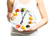 Beautiful young woman holding a plate with food, diet and time concept close up 