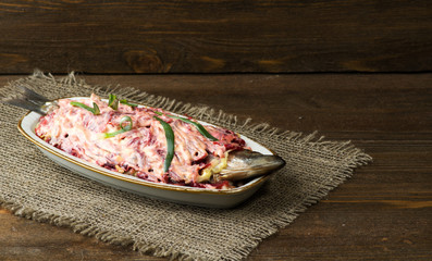  salad herring under a fur coat on a wooden table in the backgro