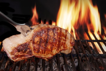 Pork Loin Steak On Hot Flaming Barbecue Grill With Fork