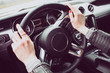 © Laszlo - Close up image of female driver hands on the steering wheel. Red painted nails.