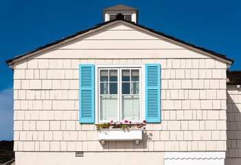 white wooden facade with blue shutters and flowers