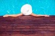 © WavebreakMediaMicro - Woman wearing hat leaning on wooden deck by poolside