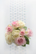 Ein Rosenstrauß mit rosa und weißen Blüten steht auf einen weißen Tisch 