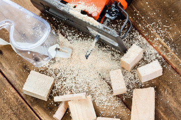 Wall Mural - Electric jigsaw with many wooden bricks full of sawdust.