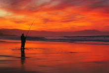 Fisherman Silhouette On Beach At Sunset