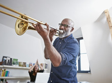 Portrait Of Man Playing Trombone At Home Office