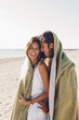 © Westend61 - Romantic young couple together at the beach wrapped in a blanket