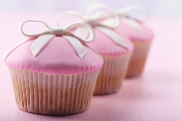 Wall Mural - Tasty cupcakes with bow on color wooden background