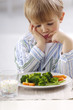 © Westend61 - Portrait of little blond boy looking at plate with vegetables