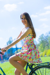 Young pretty woman riding bike in park