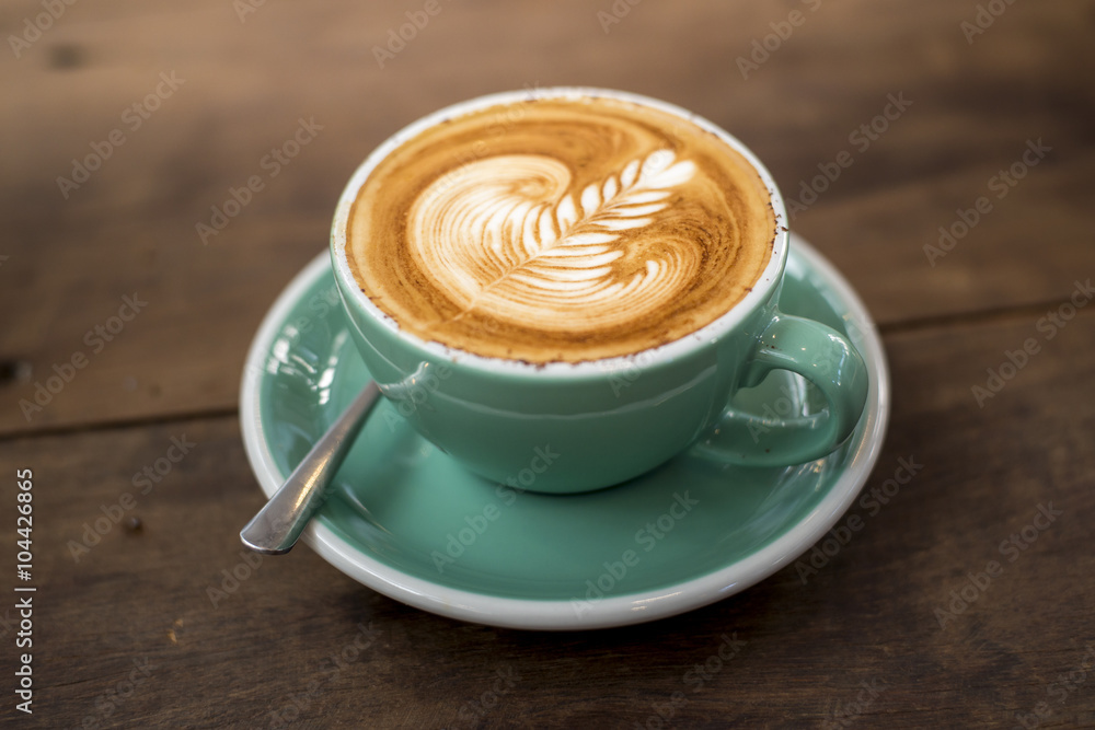 hot cappuccino with latte art on wood background