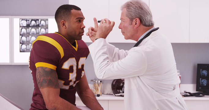 Wall Mural -  - College football player having senior doctor review his concussi