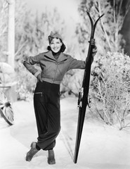 Woman standing in the snow with her skies in hand 