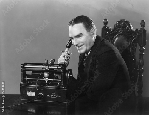 Fotomural Smiling man using Dictaphone