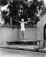 Woman on diving board at swimming pool 