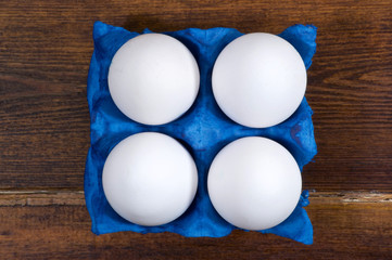 Wall Mural - White eggs in navy blue container closeup