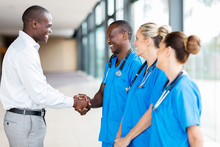 Medical Rep Handshaking With Group Of Doctors