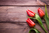 Fototapeta Kwiaty - Red tulips flowers on wooden desks.