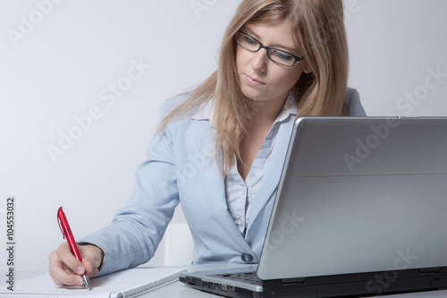 Fotografie, Obraz Junge Frau arbeitet gewissenhaft im Büro am Laptop
