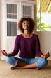 © mimagephotos - African american woman practising yoga at home