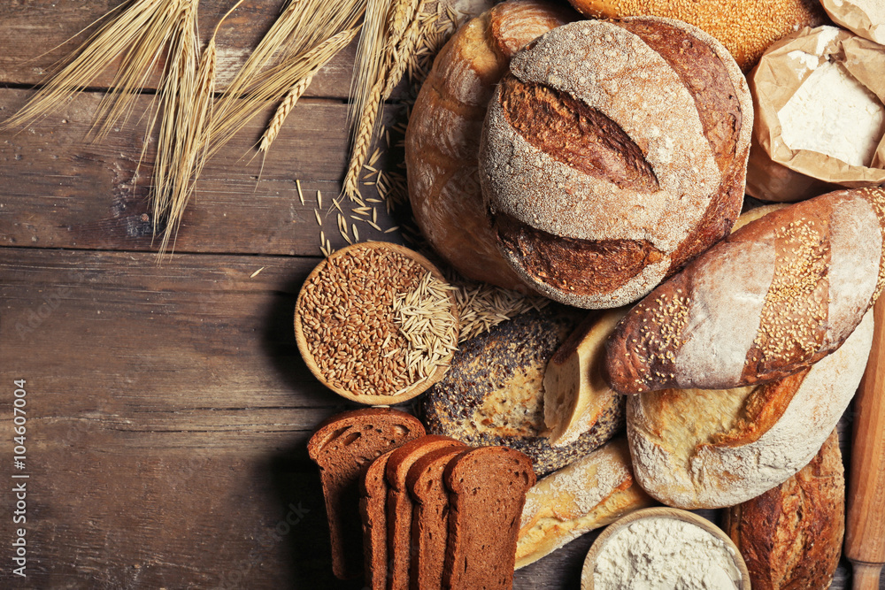 Fresh baked bread, flour and wheat on the wooden background