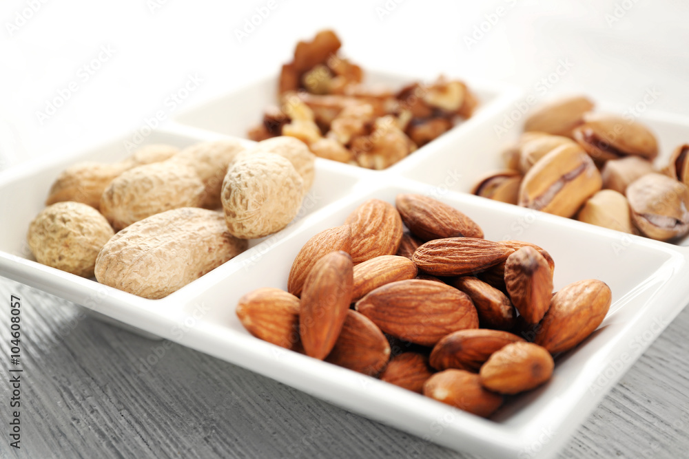 Walnut kernels, almonds, pistachios, peanuts in the ceramic rectangle plate, close-up