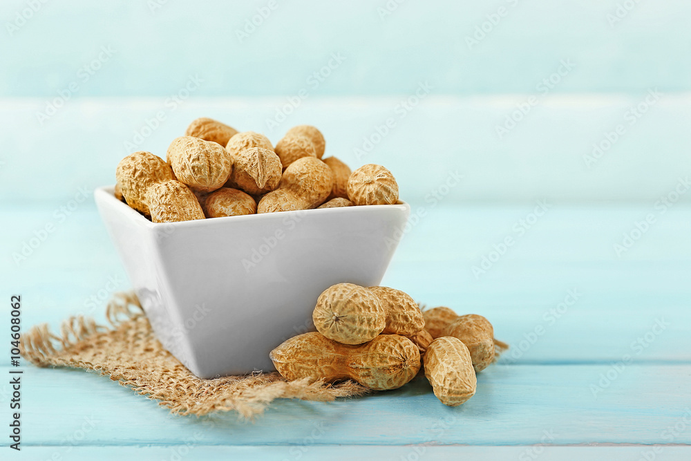 Peanuts in the bowl on blue wooden background
