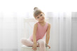 © Africa Studio - Little cute girl in pink leotard sitting on chair at dance studio