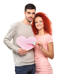 Poster - Young couple in love holding paper pink heart and key, isolated on white