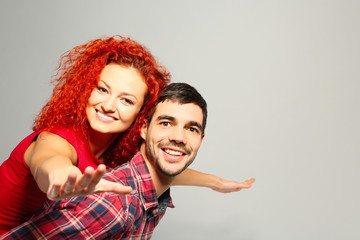 Poster - Young couple in love having fun on grey background