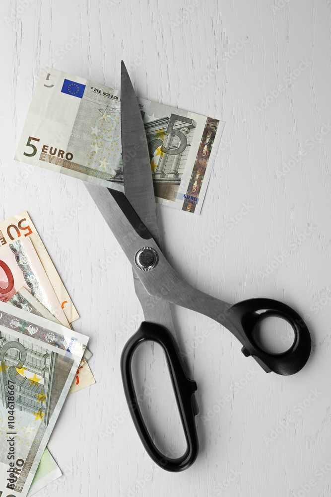 Scissors cuts euro banknote on table