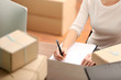 © Africa Studio - Delivery concept. Woman signs papers among parcels, close up