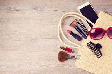 Woman bag with makeup and fashion objects. View from above