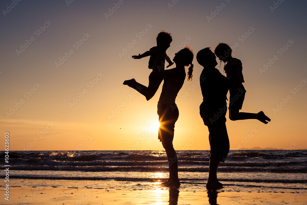 Silhouette of happy family who playing on the beach at the sunse - obrazy, fototapety, plakaty 