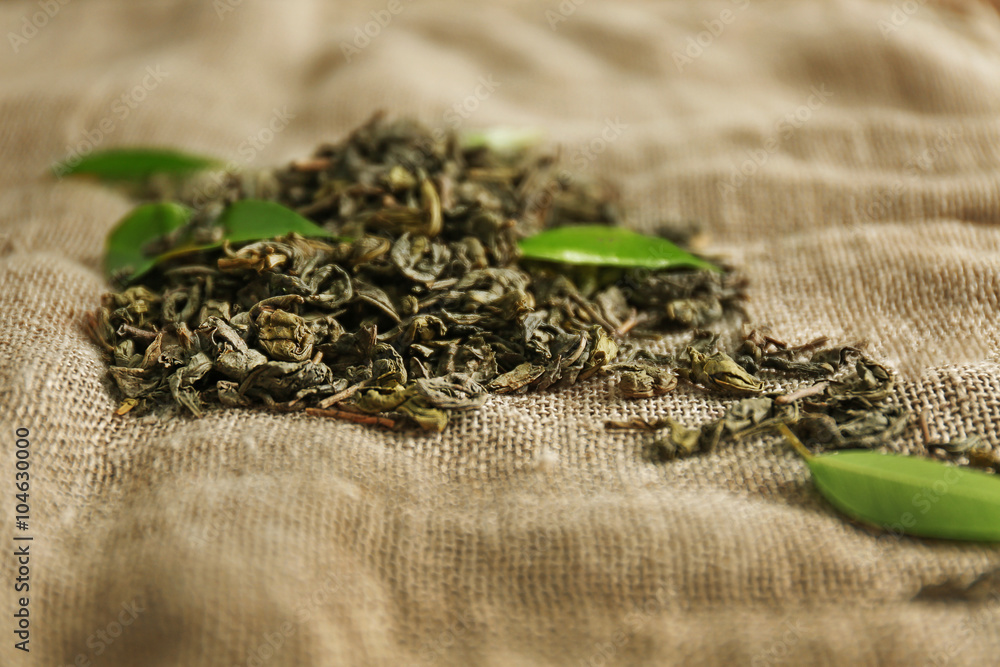 Granulated tea with green leaves on sackcloth background