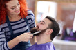 Professional hairdresser cutting beard with scissors
